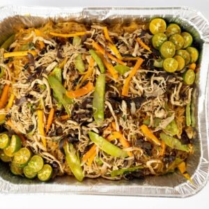 Delicious Pancit Bihon with vegetables and calamansi in an aluminum tray, top view.