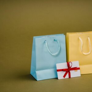 Collection of bright present paper bags with natural handles near gift card with ribbon